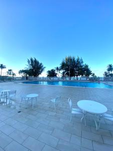 Un patio con mesas y sillas frente a una piscina. en Downtown Beachfront Isla Verde Tropical Apartment, en San Juan