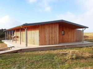 a wooden house with a deck in a field at 8 person holiday home in Vestervig-By Traum in Vestervig