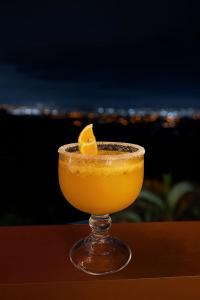 a glass of orange juice with a lemon on a table at Hotel Mirador Mayday Mountain View in Alajuela City +65 photos