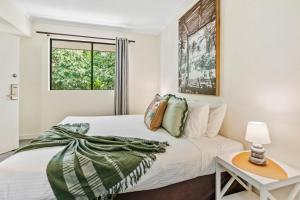 a white bedroom with a bed and a table at Palm Cove Studio Pools Spa Bar in Palm Beach
