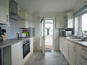 a kitchen with white cabinets and a sink at Headlands House - Uk6739 in Lydstep