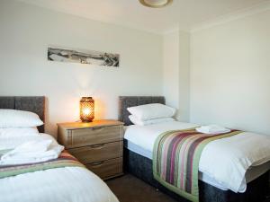 a bedroom with two beds and a lamp on a dresser at Headlands House - Uk6739 in Lydstep +7 photos