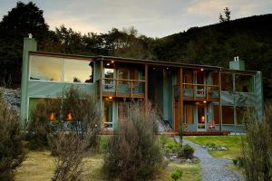 a large green house with a balcony on a hill at Wilderness Lodge Arthurs Pass in Arthur's Pass