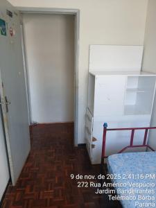 een kamer met een koelkast en een deur bij Kitnet na Band in Telêmaco Borba +3 foto's