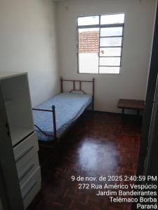 een kleine slaapkamer met een bed en een raam bij Kitnet na Band in Telêmaco Borba