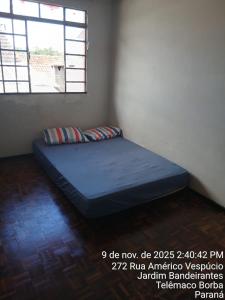 een bed in een hoek van een kamer met een raam bij Kitnet na Band in Telêmaco Borba