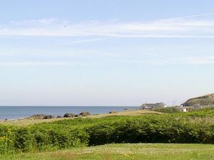 Un campo verde con el océano al fondo en Braemar, en Lendalfoot