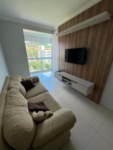 een woonkamer met een bank en een flatscreen-tv bij Brisa do Sol Apartment 201 - Piratuba SC in Piratuba