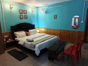 a bedroom with a large bed and a red chair at Nirvana River Nest in Sainj