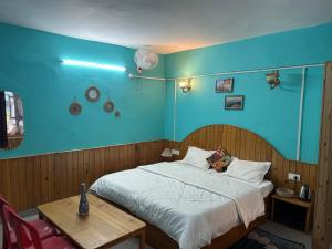 a blue bedroom with a bed and a table at Nirvana River Nest in Sainj