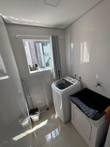 een wasruimte met een wasmachine en een raam bij Brisa do Sol Apartment 201 - Piratuba SC in Piratuba