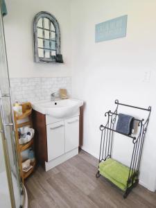 ein weißes Badezimmer mit Waschbecken und Spiegel in der Unterkunft CROOKED MILE COTTAGE - BY THE SEA - family friendly in Hokitika