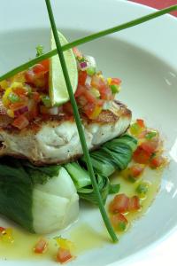 a white plate with a piece of fish with salsa at Wilderness Lodge Arthurs Pass in Arthur's Pass