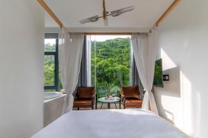 a bedroom with a bed and a tub and a window at Sheng Hai Yun Ju in Zhuhai
