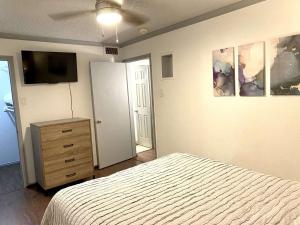 a bedroom with a bed and a dresser and a television at 1BD condo DFW South I10 in Sowers +5 photos