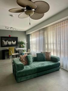 Un sofá verde en una sala de estar con un ventilador de techo. en South Point Cozy Apartment, en Miami Beach