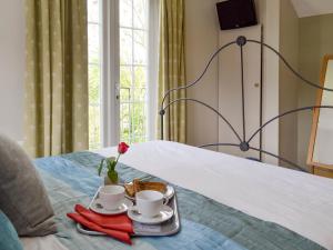 a tray with two cups and a flower on a bed at Holly Cottage in Pett +11 photos