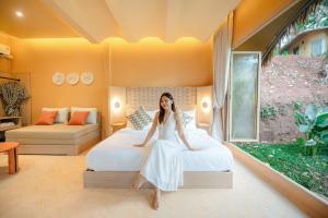 a woman in a white dress sitting on a bed at Lazula in Ban Pok Nai +12 photos