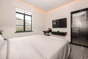 a white bedroom with a large bed and a tv at 烟台朝阳文保艺术酒店 in Yantai