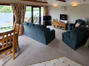a living room with two blue couches and a television at Heron's View - 28279 in Brundall