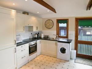 a kitchen with a washing machine and a clock on the wall at Heron's View - 28279 in Brundall