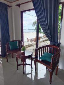 ein Zimmer mit 2 Stühlen, einem Tisch und einem Strand in der Unterkunft Theresia Bin Cottage in Ngurblut