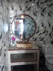 Eine Frau, die ein Bild von einem Badezimmer mit einem Spiegel macht. in der Unterkunft Theresia Bin Cottage in Ngurblut