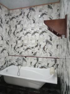 eine Badewanne in einem Badezimmer mit Marmorwand in der Unterkunft Theresia Bin Cottage in Ngurblut