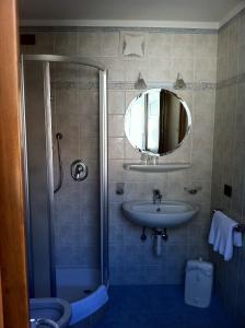 uma casa de banho com um chuveiro, um lavatório e um espelho. em Pensione Edelweiss em San Cassiano