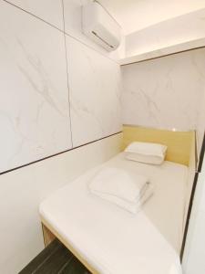 una pequeña habitación blanca con dos toallas sobre un banco en Joy Hella Inn, en Hong Kong