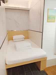 a small bed with white sheets and pillows on it at Joy Hella Inn in Hong Kong