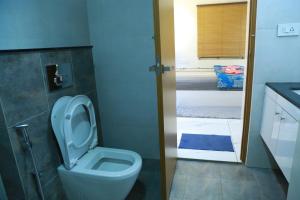 a bathroom with a toilet with the seat up at The Crownstone Apartment in Trivandrum +22 photos