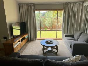 Una sala de estar con un sofá, un televisor y una mesa. en Central Comfort, en Shepparton