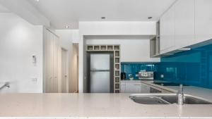 アポロ・ベイにあるTriplet Apollo Bayのキッチン(青と白のキャビネット、シンク付)