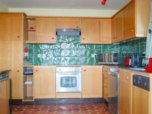 een keuken met houten kasten en een kookplaat met oven bij Callachy Cottage - Uk7047 in Glenurguhart