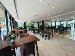 a restaurant with wooden tables and chairs and windows at The Green Hotel Vientiane in Vientiane