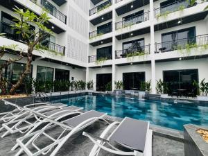 a hotel swimming pool with lounge chairs in front of a building at The Green Hotel Vientiane in Vientiane