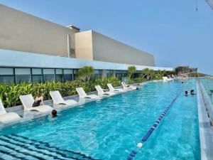 a swimming pool with white chairs and people in it at Ocean Pearl The Sóng Apartment - Vung Tau City - Căn Hộ View Biển, Hồ Bơi Vô Cực in Vung Tau