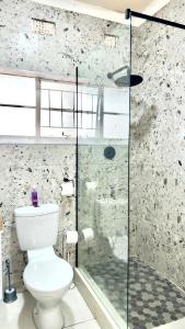 Un baño con inodoro y ducha de cristal. en Seaside Studio 22, en East London