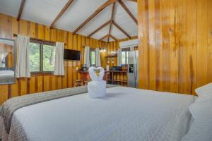 Un dormitorio con una gran cama blanca con paredes de madera. en Kmar Villas, en Placencia Village