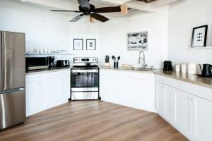 a kitchen with white cabinets and a ceiling fan at Luxury Oceanview Villa Walk to Beach & Dining in Enighed