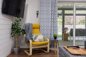 Una silla amarilla en una sala de estar con un televisor. en Coho Trailside Comforts, en Brackendale