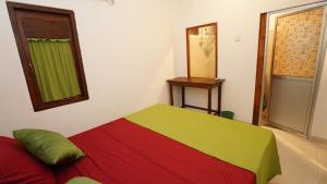 a bedroom with a red and green bed and a mirror at New Morning Hikkaduwa in Hikkaduwa +3 photos