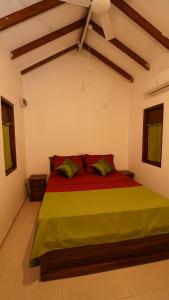 a bedroom with a bed with red sheets and green pillows at New Morning Hikkaduwa in Hikkaduwa