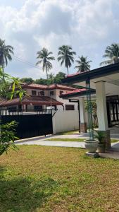 a house with a fence and palm trees at The Grace Cottage - Negombo in Dagonna