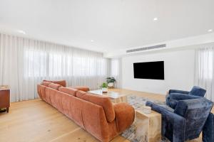 a living room with a couch and two chairs and a tv at Ebony Escape in Casuarina