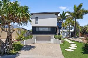 a house with palm trees and a driveway at Ebony Escape in Casuarina