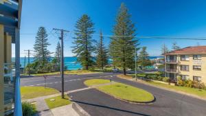 une rue vide devant un bâtiment avec des arbres dans l'établissement Seaspray Breeze, à Yamba