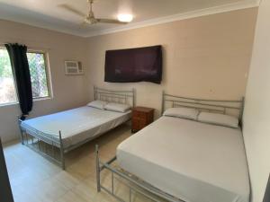 two beds in a room with a tv on the wall at Edmonton Lodge in Edmonton
