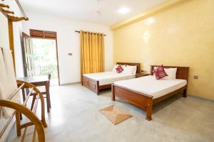a room with two beds and a table and a window at Medawatta Villa in Mirissa